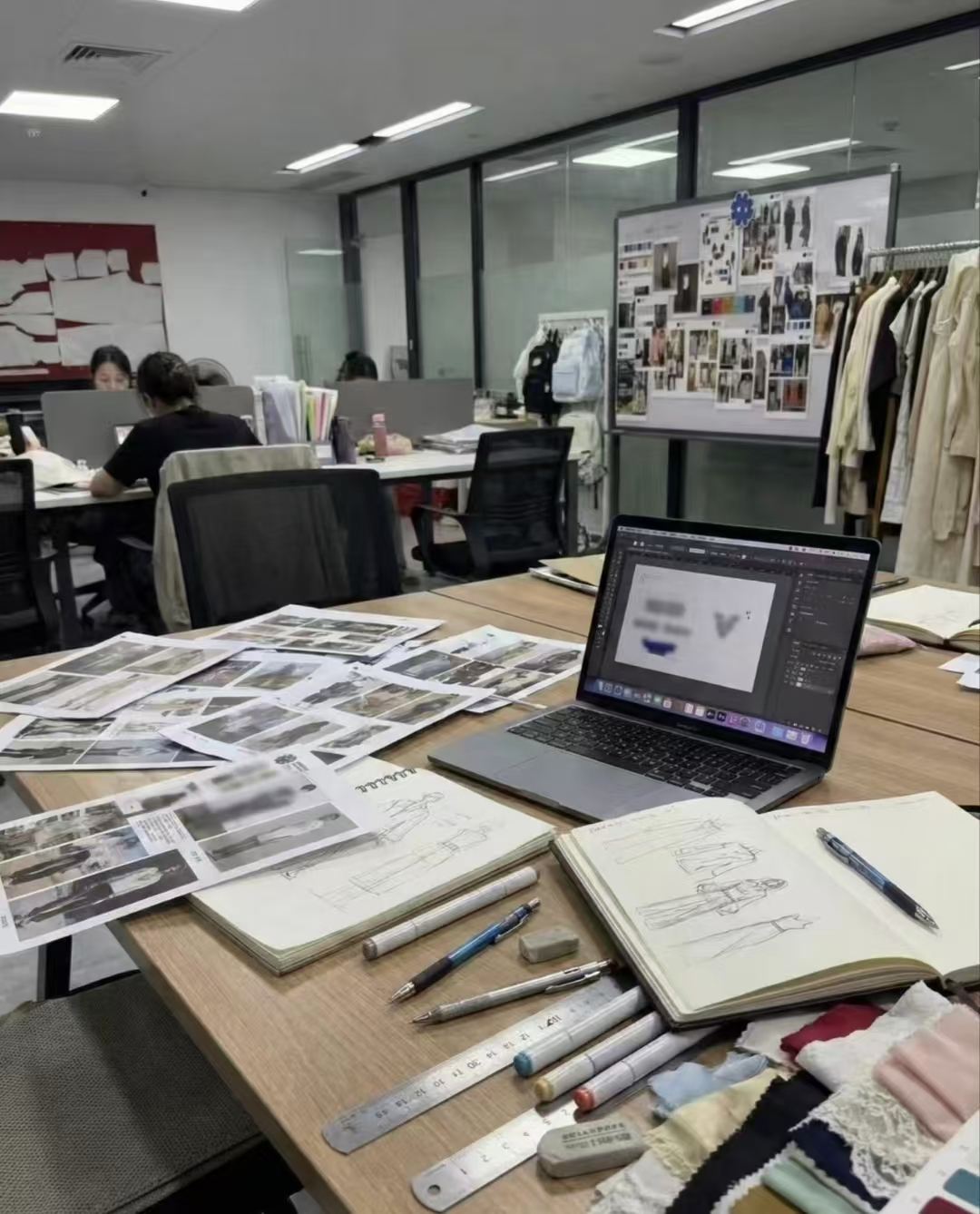 Design workbench with sketches, fabric swatches, and laptop